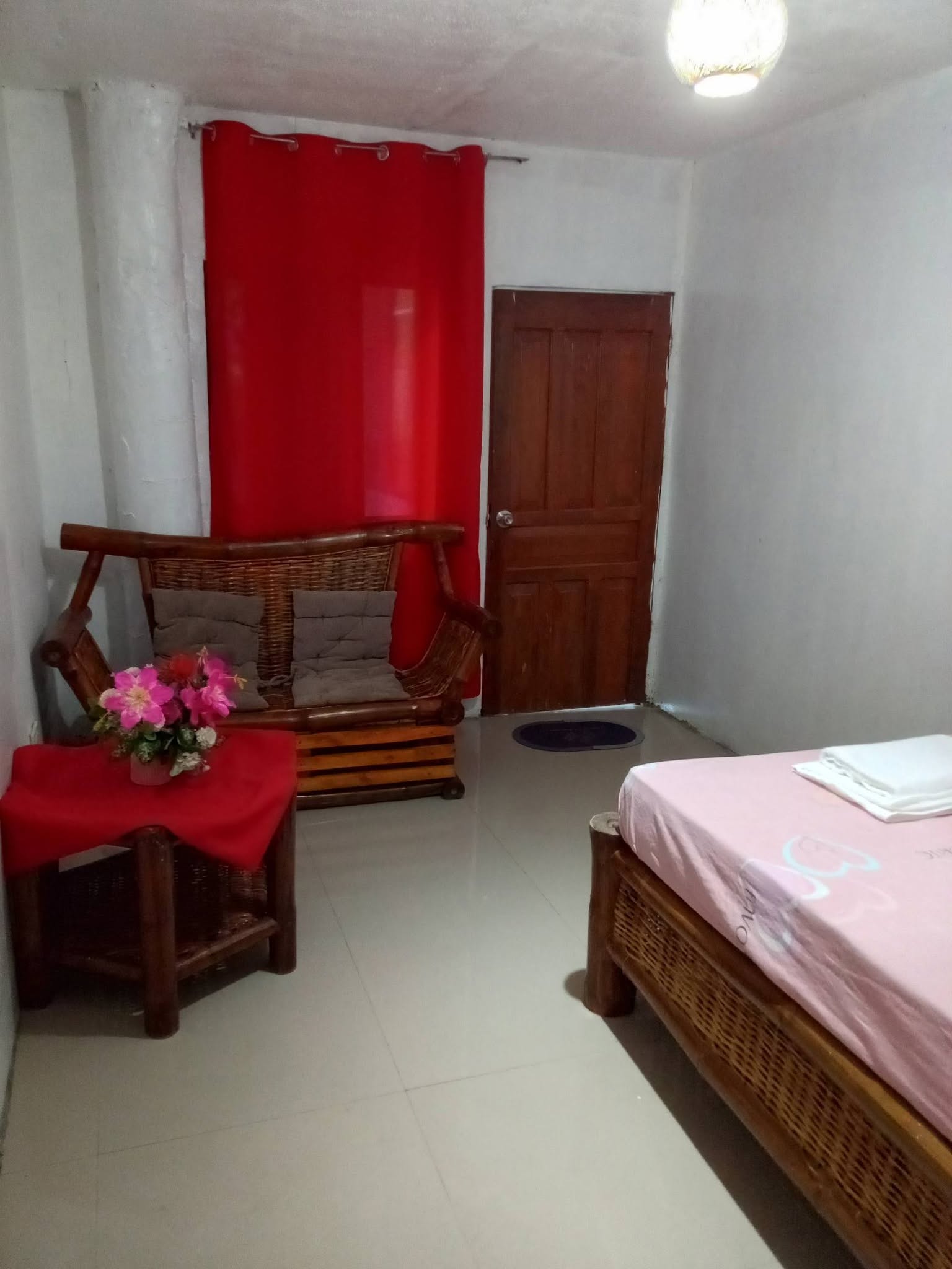 Room with a wicker sofa, side table, and a double bed